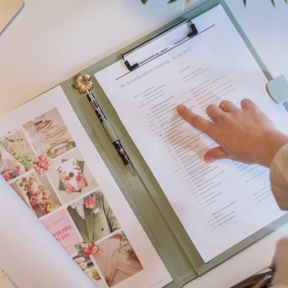 Elegant gedeckter Tisch mit orange-pinken Blumenarrangement und Gläsern.