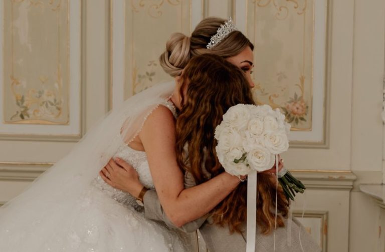 Hochzeitsplanerin Hannah in einem hellen Anzug die einen Holzstuhl auf einem Event hin und her herträgt.
