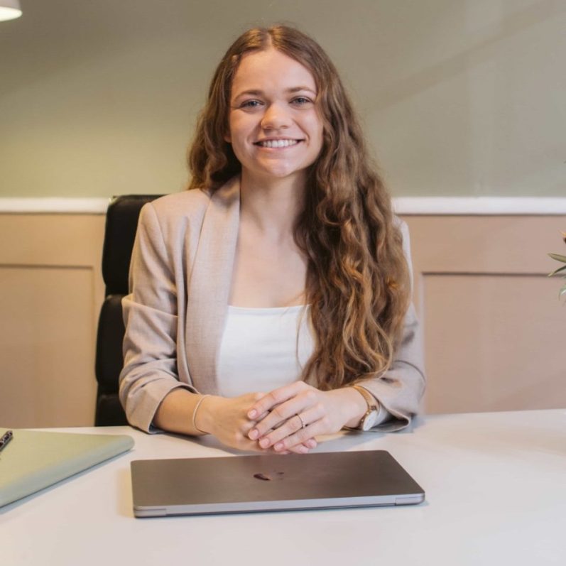 Hochzeitsplanerin Hannah und andere Absolventen in formeller Kleidung und Blumen mit Abschlusszeugnissen in der Hand vor einem weißen Haus